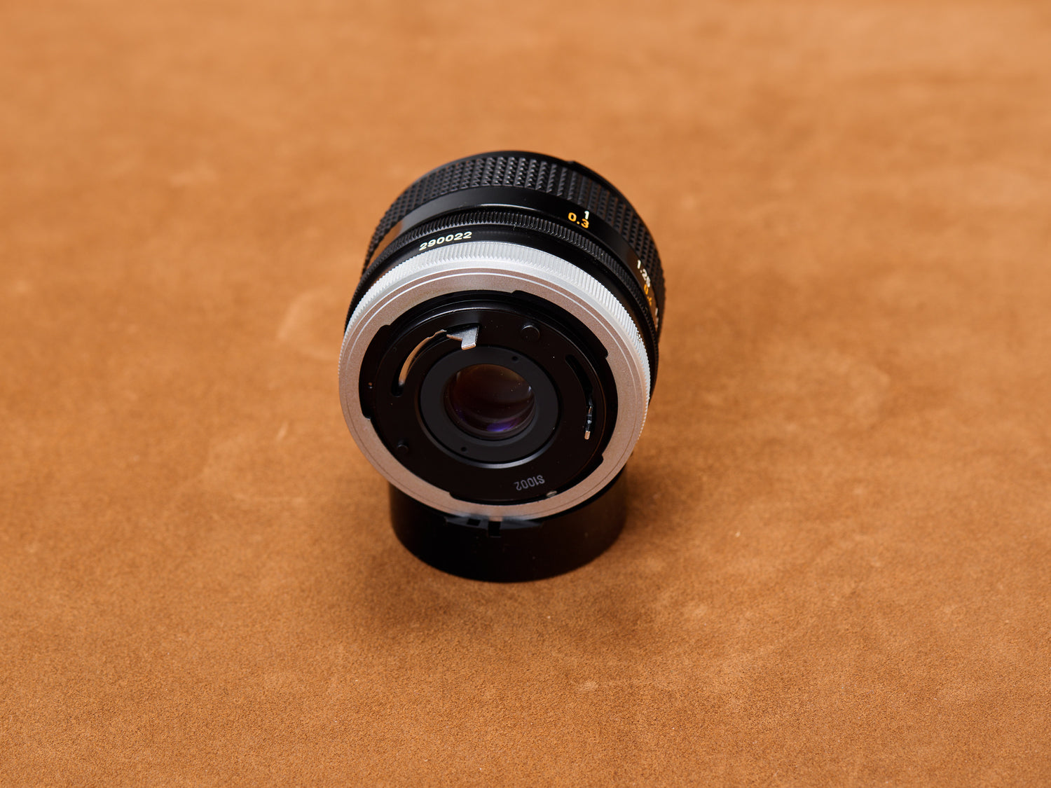 Canon 28mm f/2.8 FD rear exposed: chrome breech-lock gleaming. Rear glass silent. Serial number undeniable. Truth cornered under the lamp.