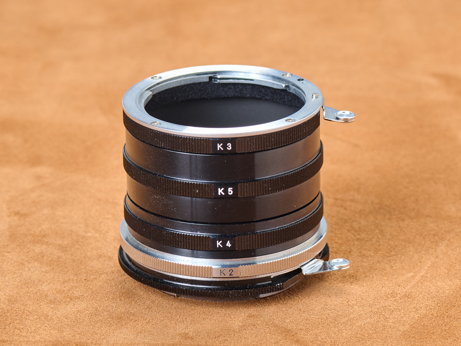 Vintage Nikon Nikkor Extension Ring Set K stacked macro tubes showing K3, K5, K4, and K2 rings on suede background