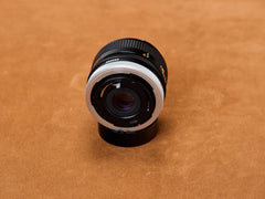 Canon 28mm f/2.8 FD rear exposed: chrome breech-lock gleaming. Rear glass silent. Serial number undeniable. Truth cornered under the lamp.