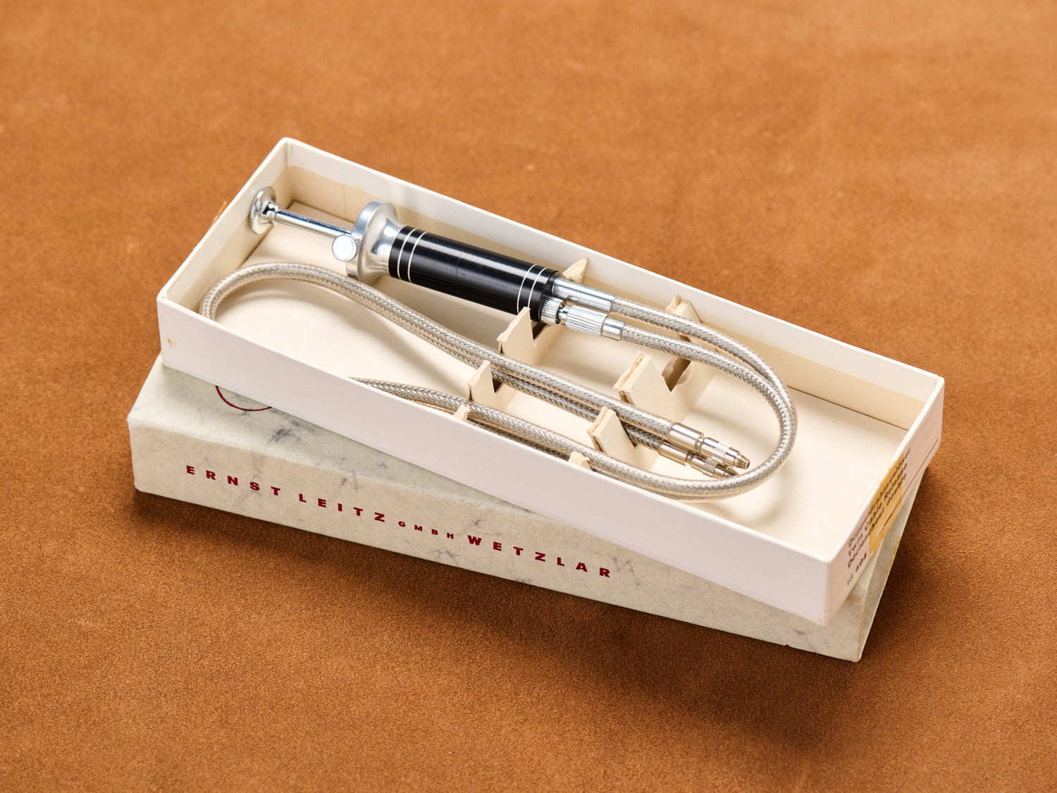 Chrome cable release, twin braided cords coiled like sin. Press once. Press twice. Double exposure, double pleasure. Box open, secrets bare.