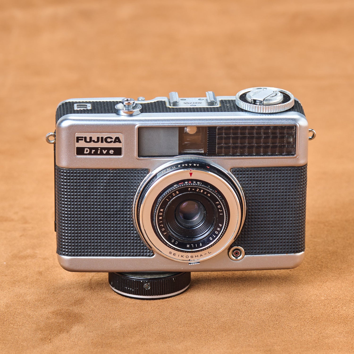 Fujica Half Drive, black leather on chrome. Spring motor coiled, hungry. Wind once. Motor devours film. Snap-snap-snap-snap. Touch it. Let it go.