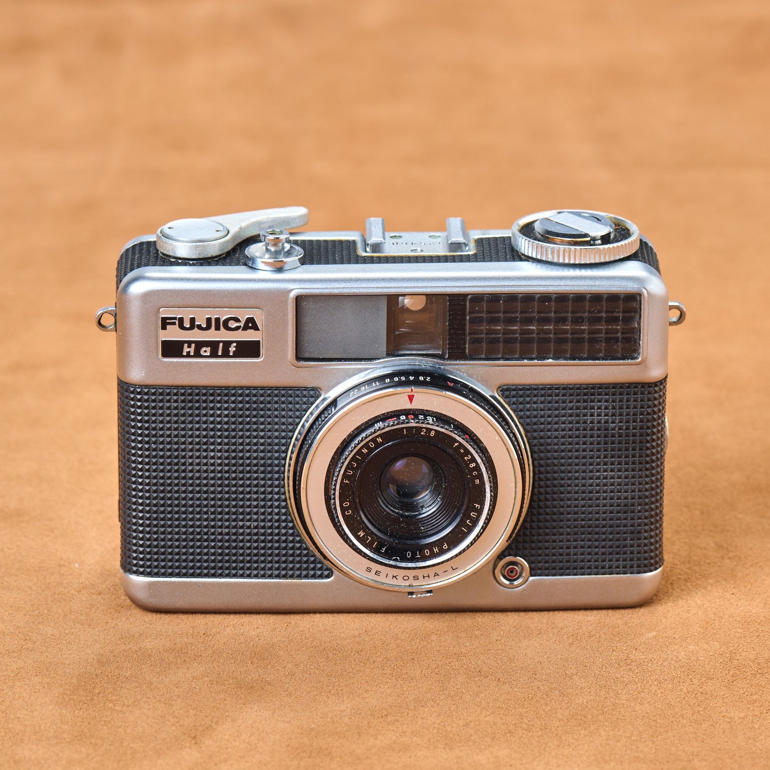 Black textured Fujica Half, chrome gleaming. Wind the lever. Feel the tension. Half-frame hunger. Snap. Again. Snap. Touch the curves. Shoot.